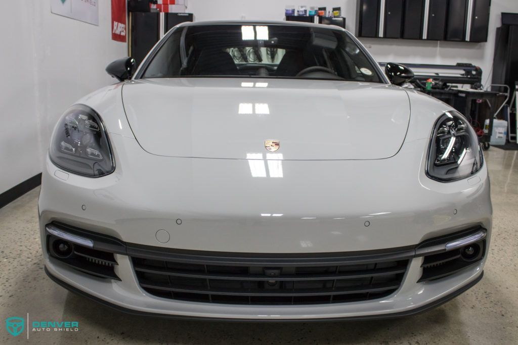 A white porsche panamera is parked in a garage.