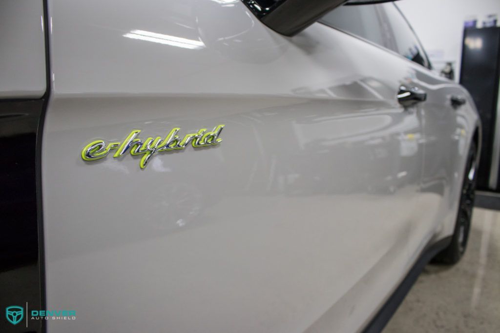 A white car with a yellow emblem on the side of it is parked in a garage.