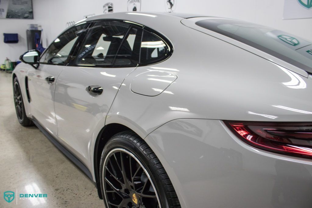 A silver porsche panamera is parked in a garage.