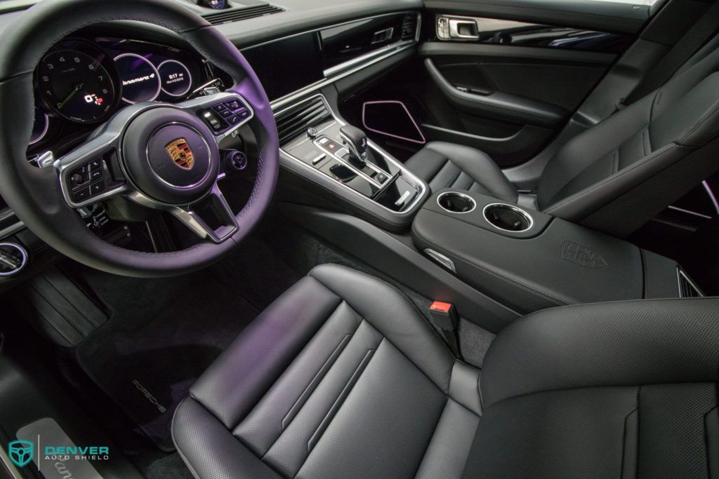 The interior of a porsche panamera with black leather seats and a purple steering wheel.