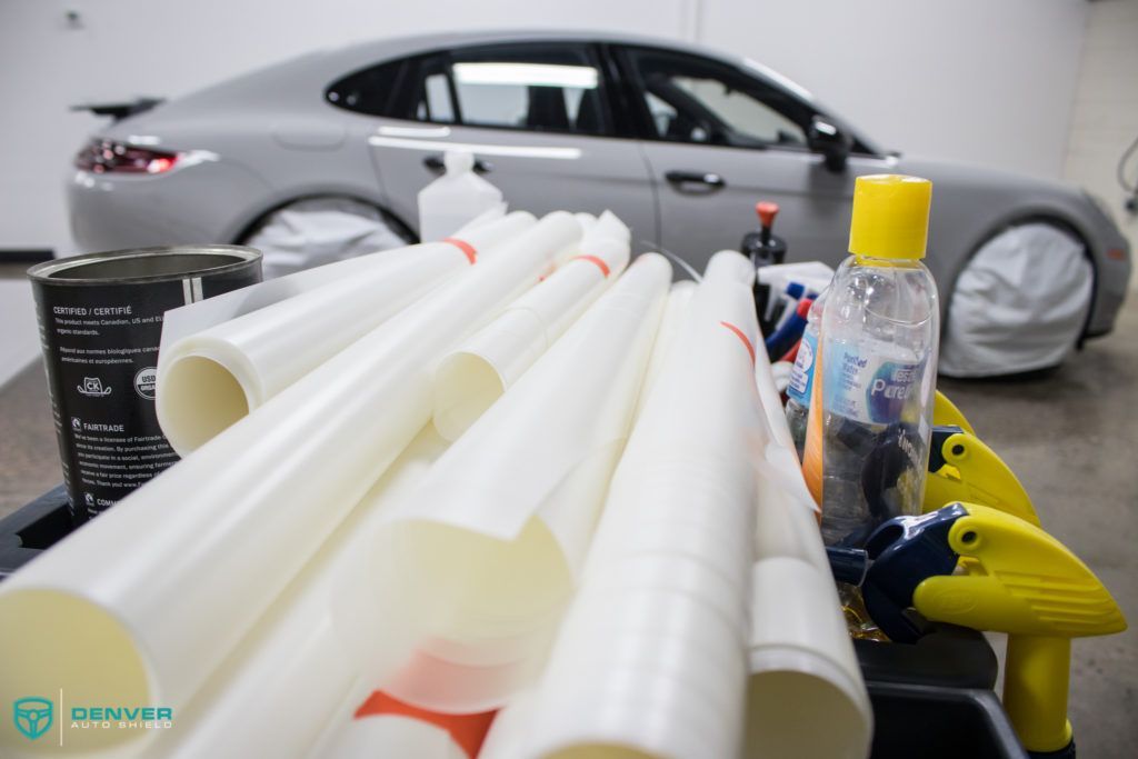 A car is sitting in a garage next to a bunch of tubes and spray bottles