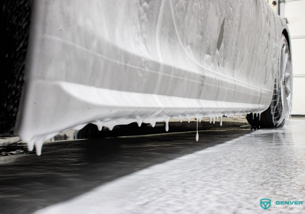 A car is covered in foam in a garage.