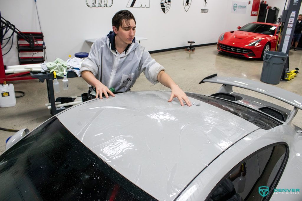 A man is working on the roof of a car in a garage.