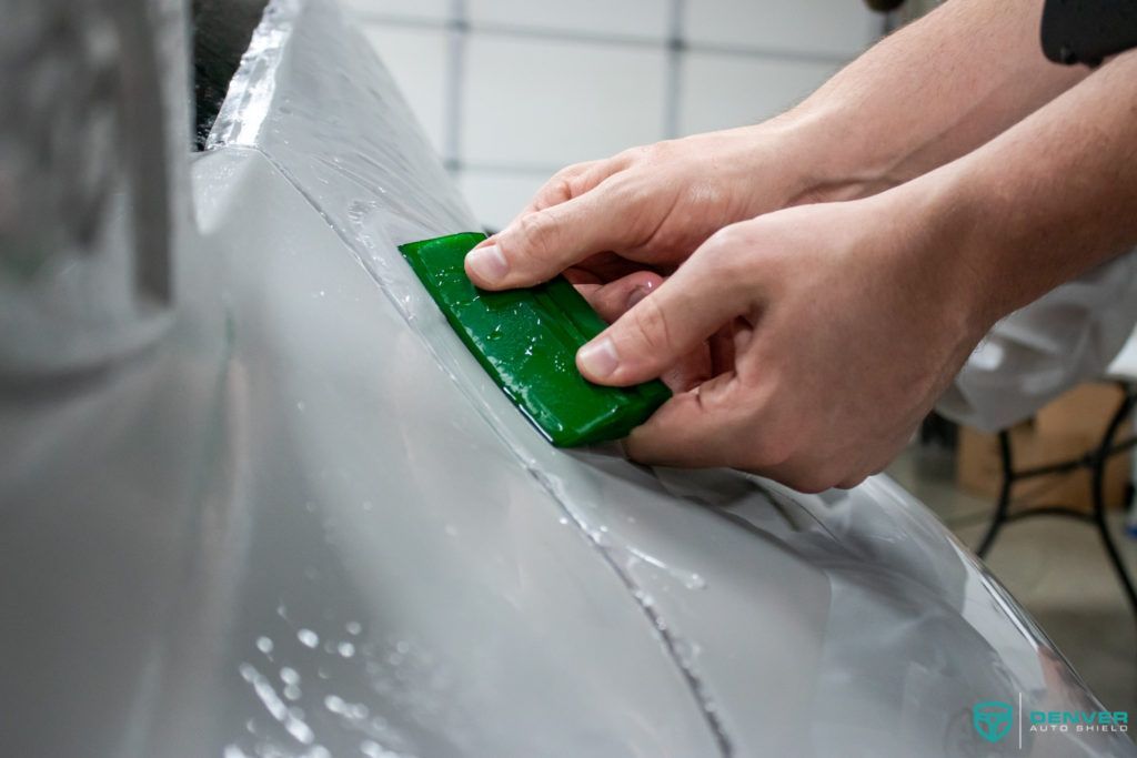 A person is cleaning a car with a green sponge.