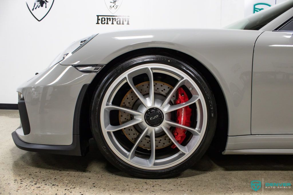 A gray porsche 911 gt3 rs with red brake calipers is parked in a garage.