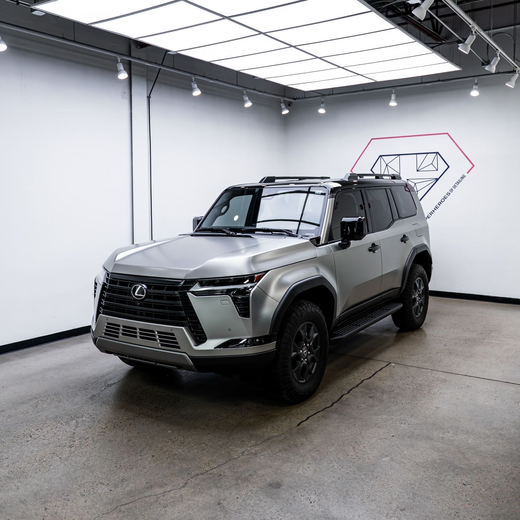 A silver lexus suv is parked in a showroom.