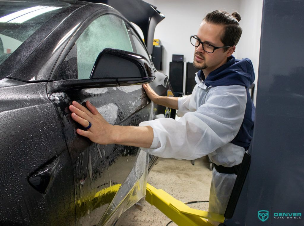 A man is wrapping a car with a protective film.