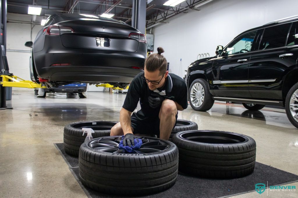 A man is working on a tesla model s in a garage.