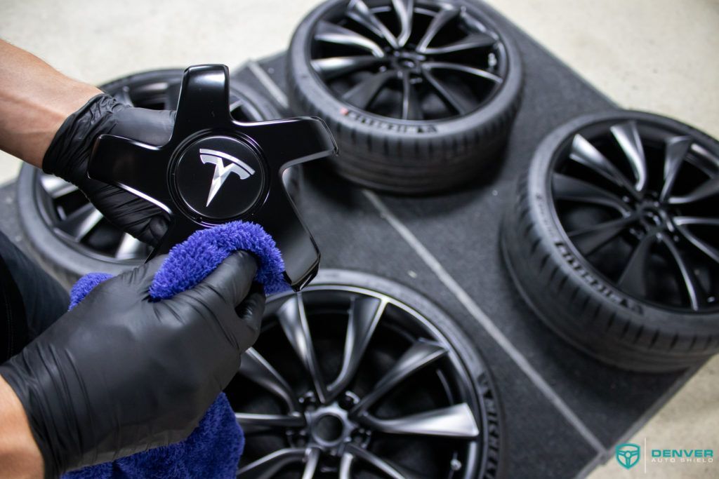 A person is cleaning a tesla wheel with a towel.