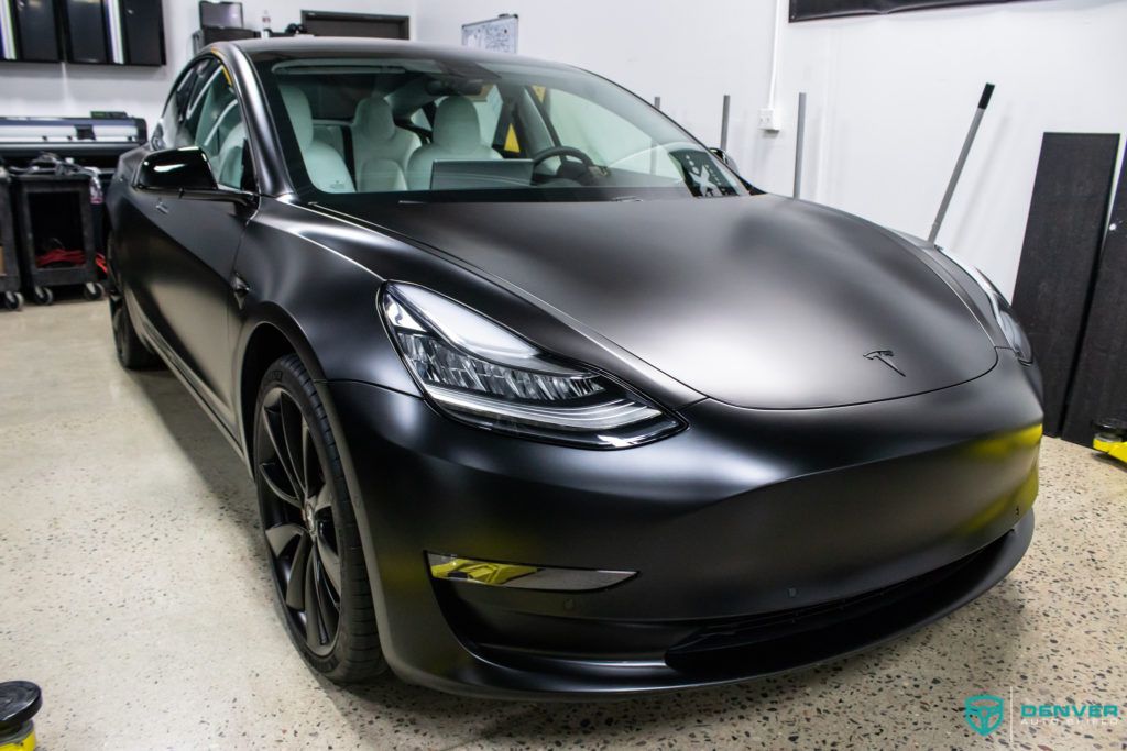 A black tesla model 3 is parked in a garage