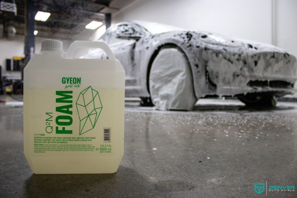 A bottle of foam next to a car covered in foam