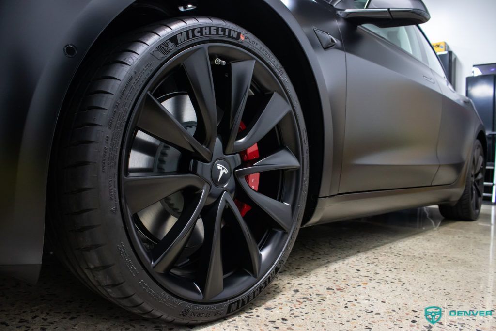 A close up of a tesla model 3 's tire in a garage.