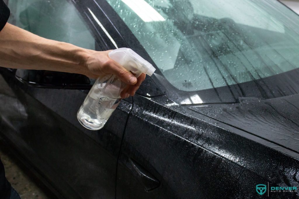 A person is spraying a car with a spray bottle.