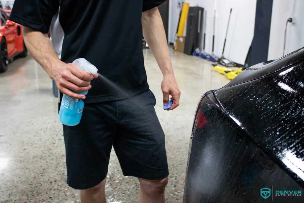 A man is spraying water on a car in a garage.