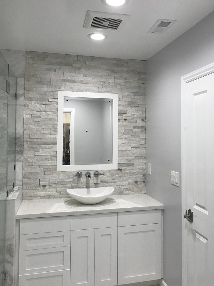 A bathroom with a sink , mirror and brick wall.