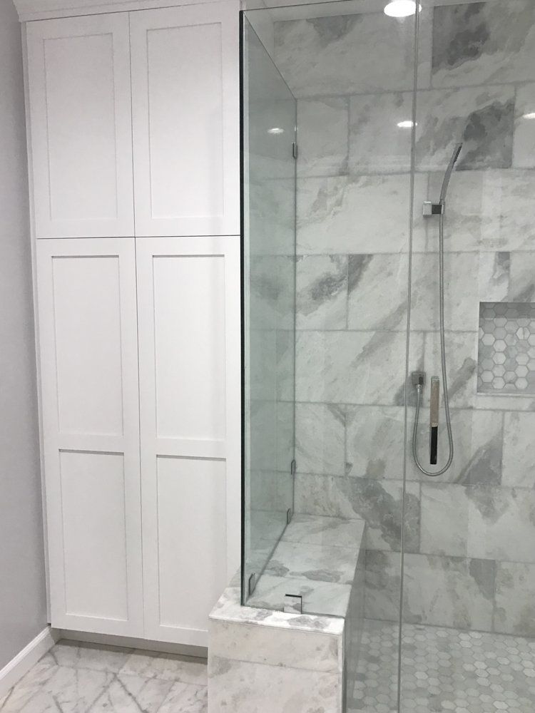 A bathroom with marble tiles and a walk in shower with a glass door.