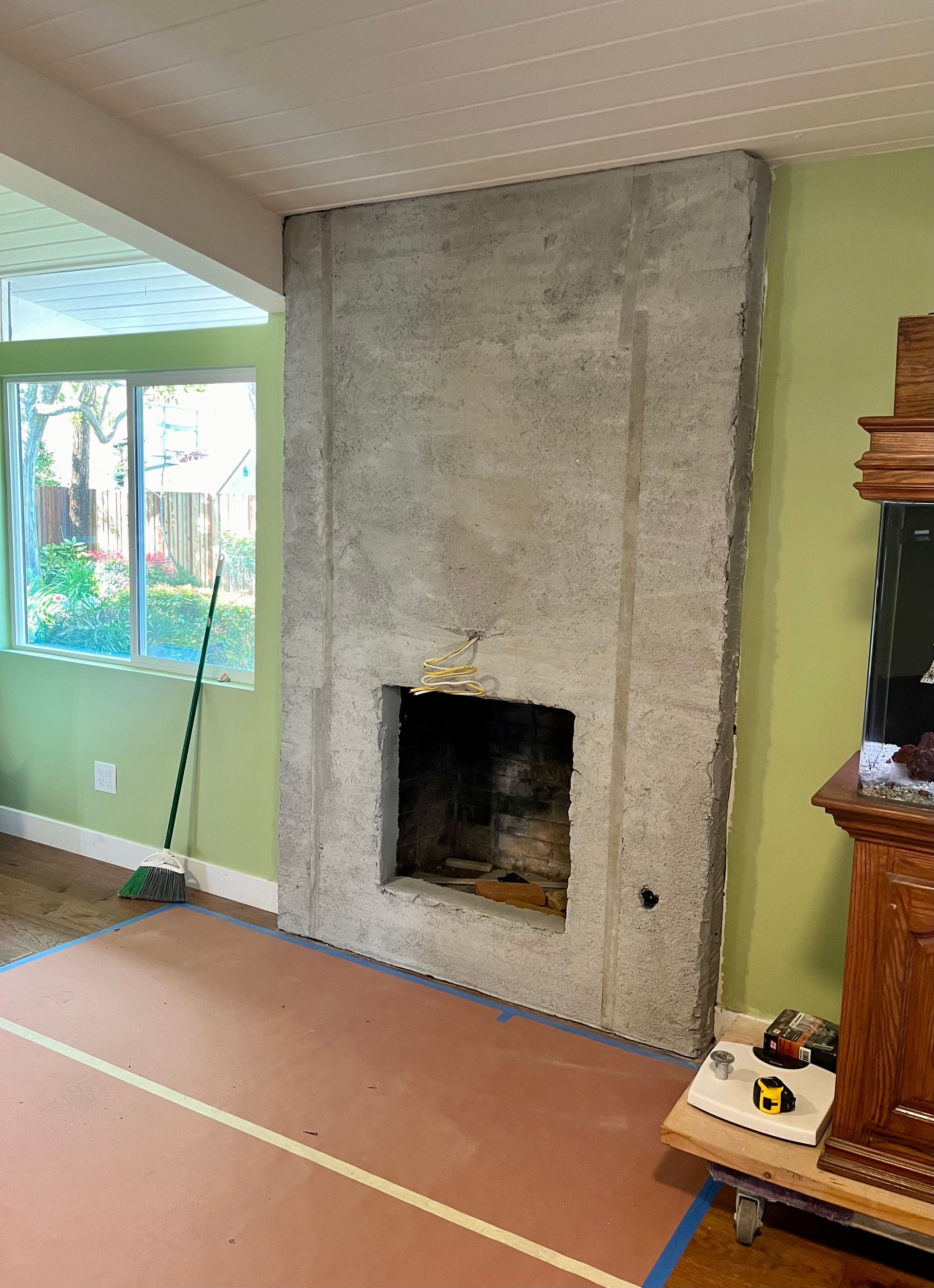 A living room with a concrete fireplace and green walls.