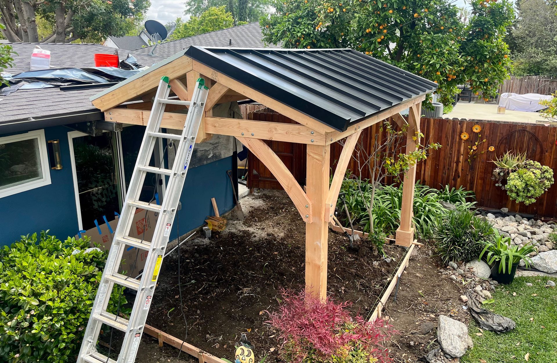 A ladder is sitting on top of a wooden structure in front of a house.