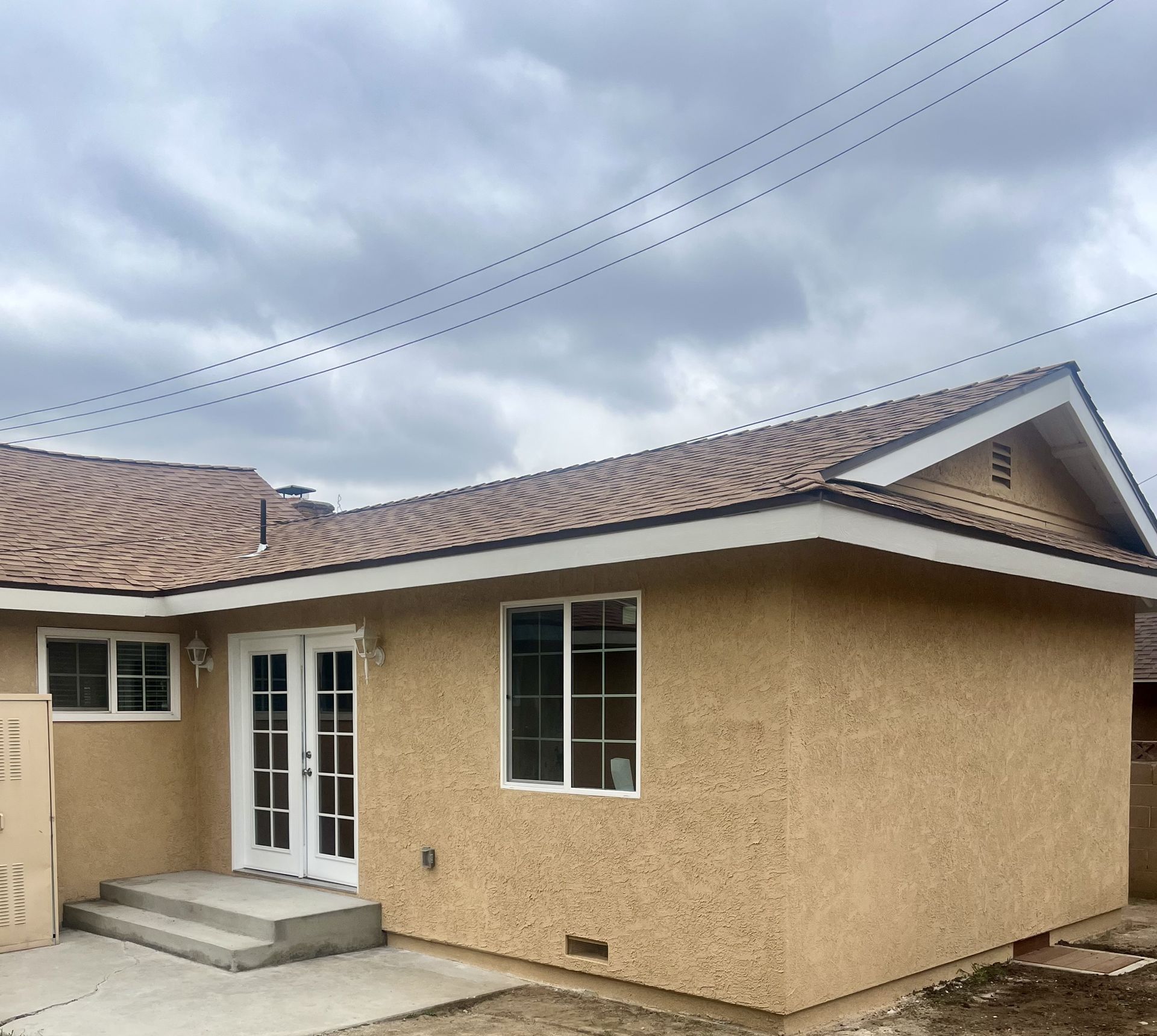 A small house with a brown roof and white windows