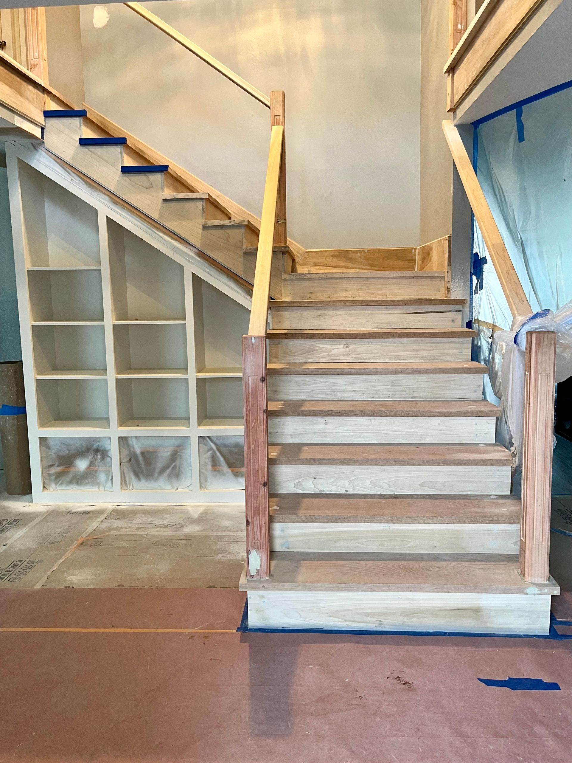 A wooden staircase with a glass railing in a room under construction