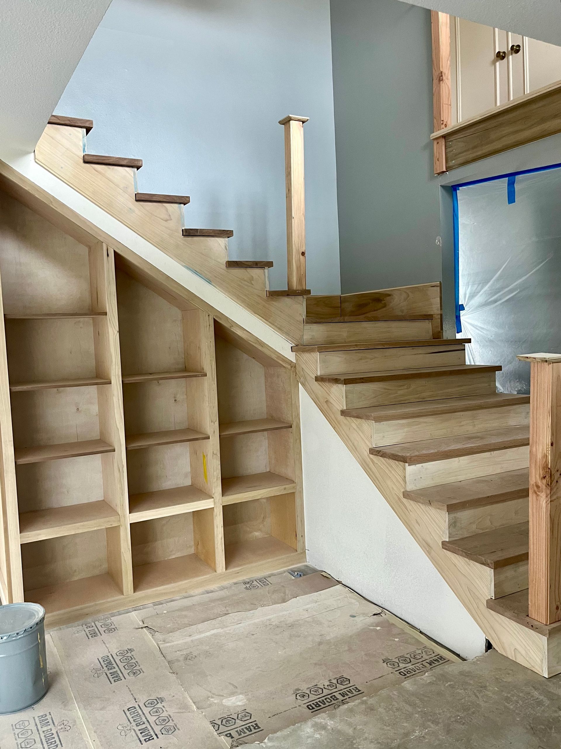 A wooden staircase with shelves underneath it in a room.