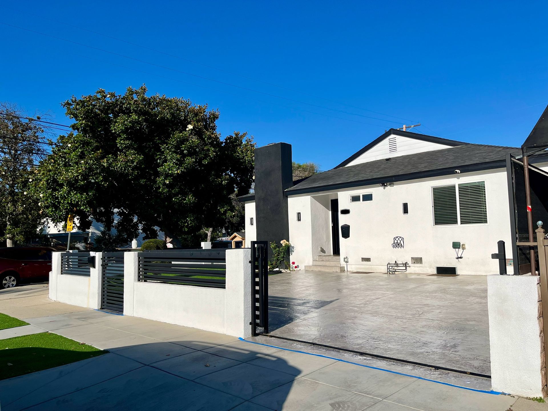 A white house with a black fence and a driveway
