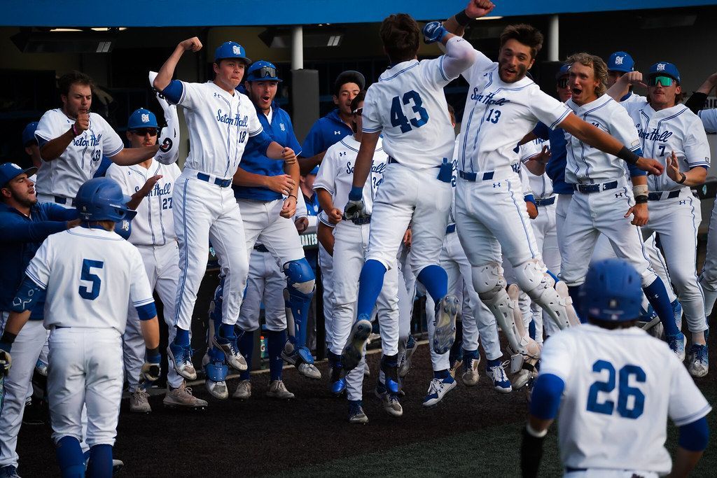 Baseball team in white uniforms celebrating a victory in the dugout, jumping and cheering