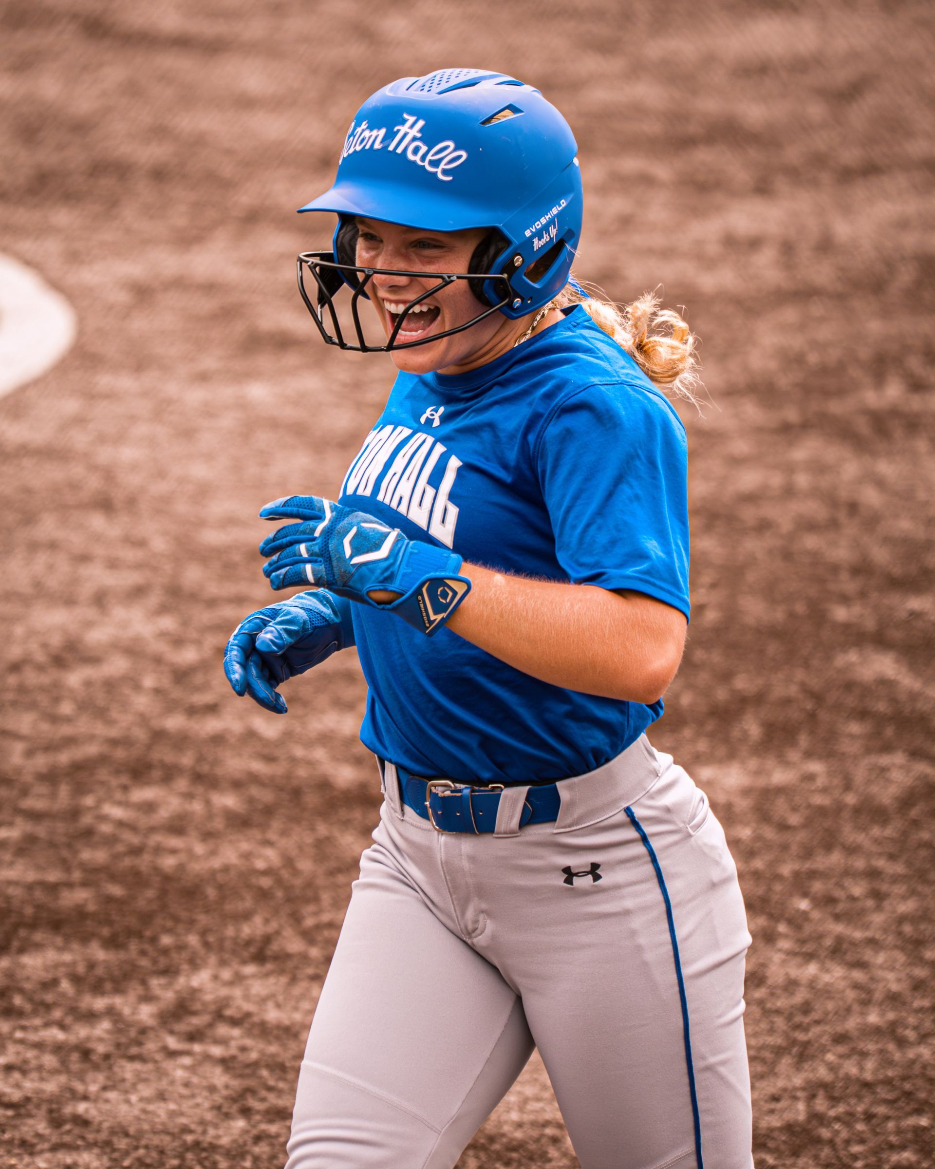 Blue-uniformed softball player in a batting helmet running on the field