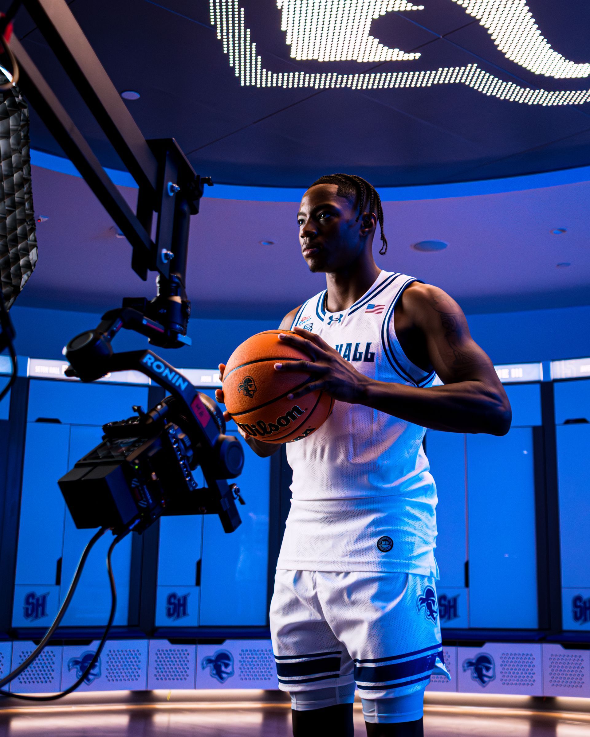 Basketball player in a white uniform posing with a ball under arena lighting