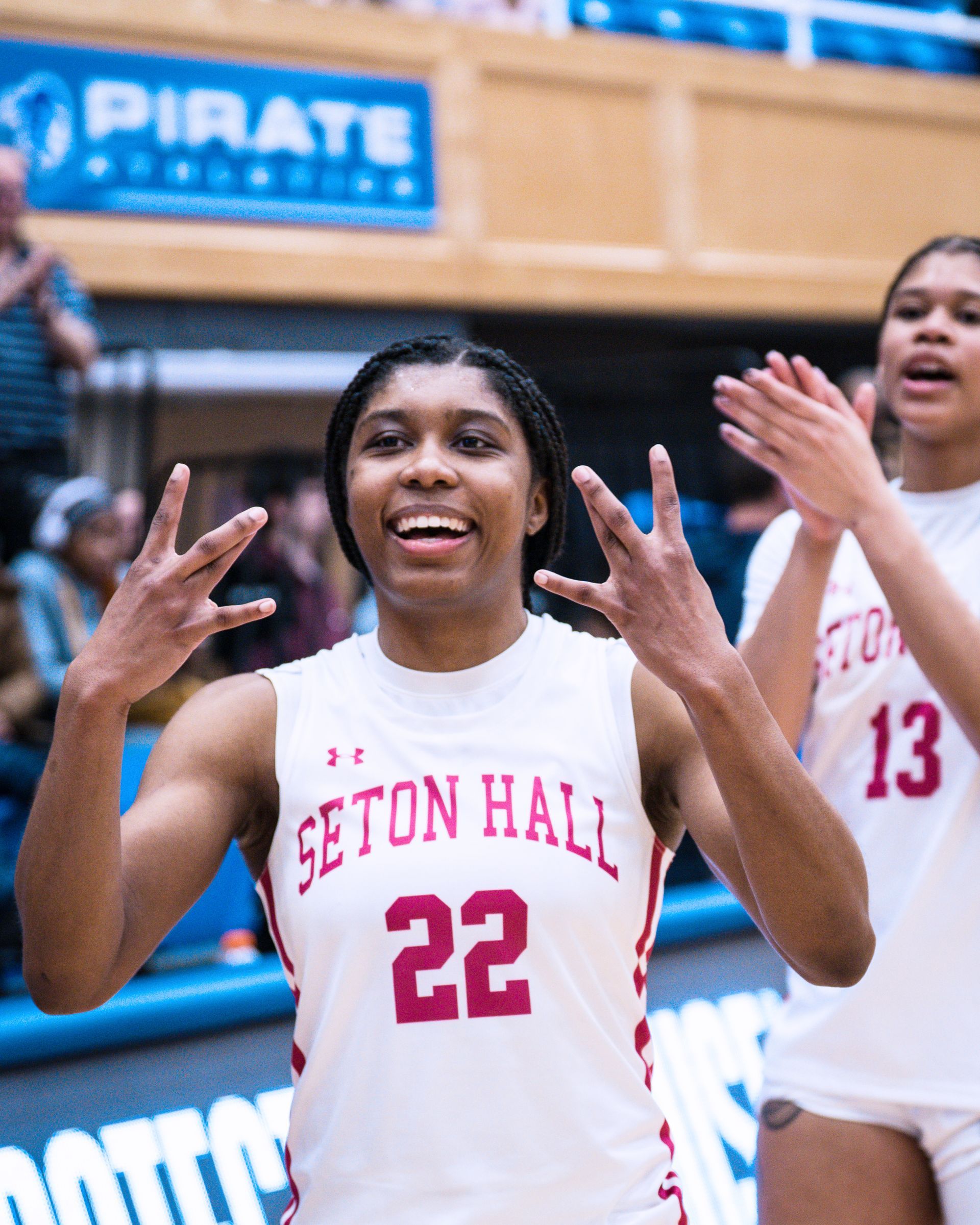 Seton Hall basketball player in white jersey #22 celebrates on court with hands raised