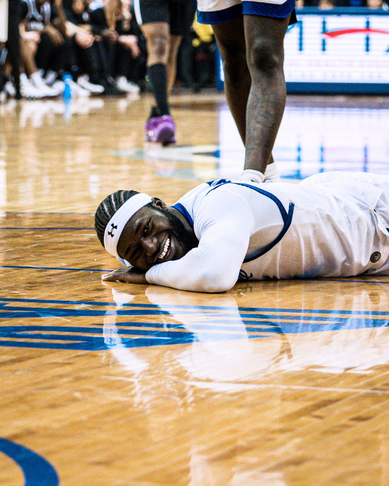 Basketball player in white lies on the court clutching an injury during a game