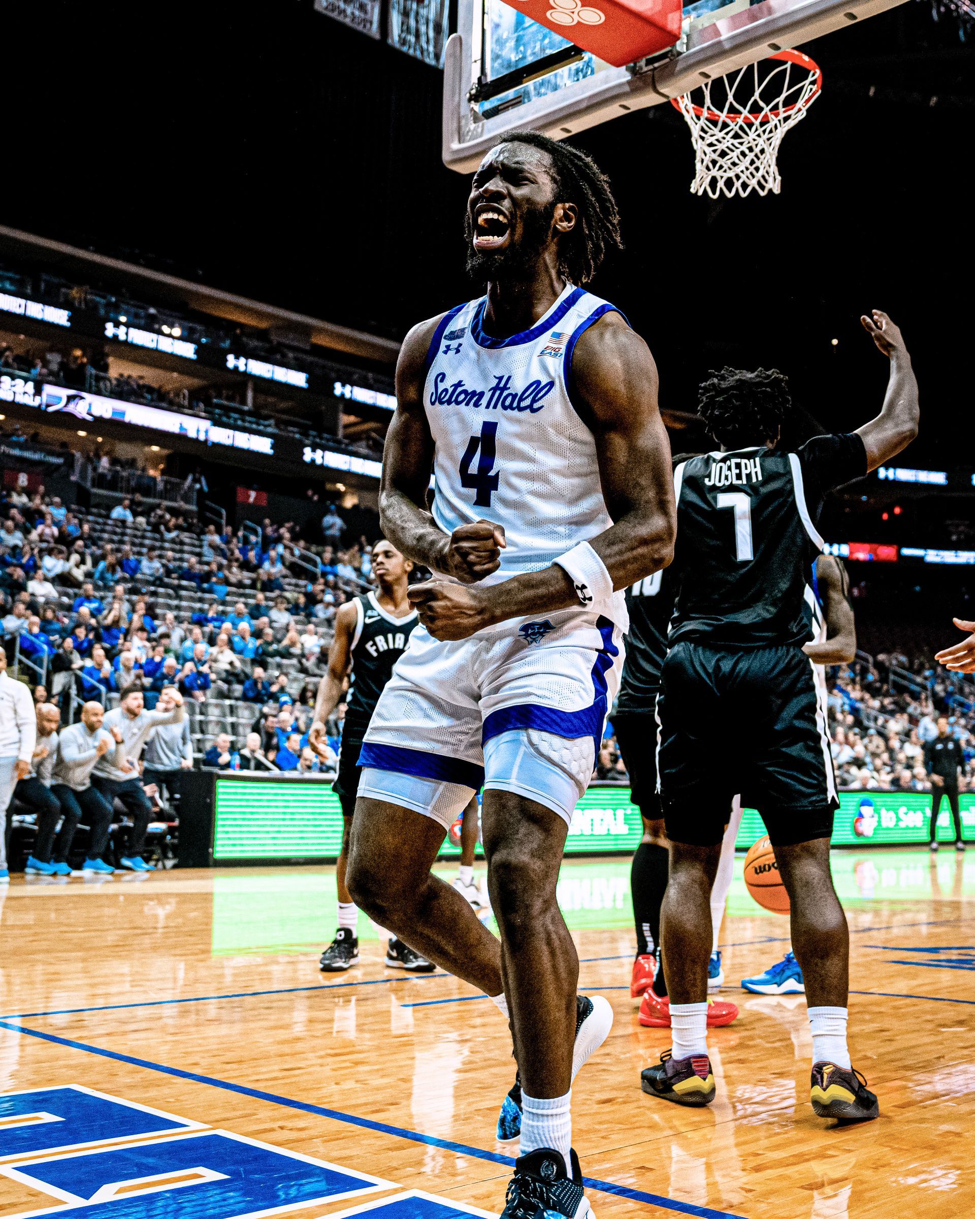 Basketball player in white jersey celebrating under the hoop during a game