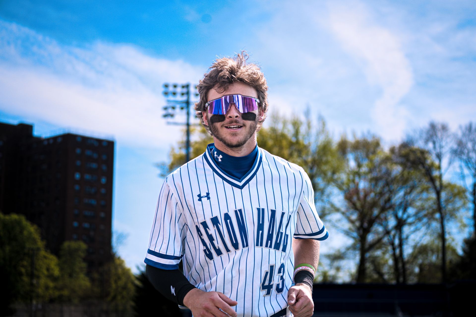 Person in a white patterned jersey and reflective sunglasses outdoors on a sunny day