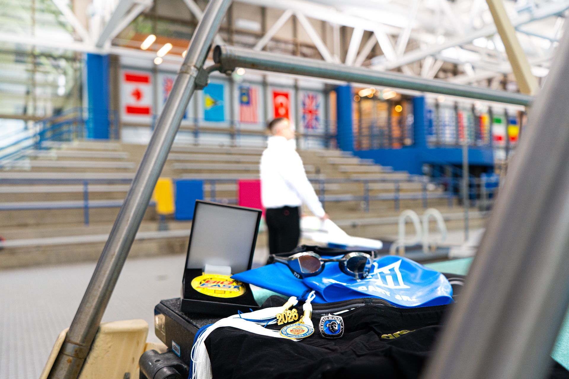 Blue racing kart with helmet on a ramp beside stadium steps and a person in the background