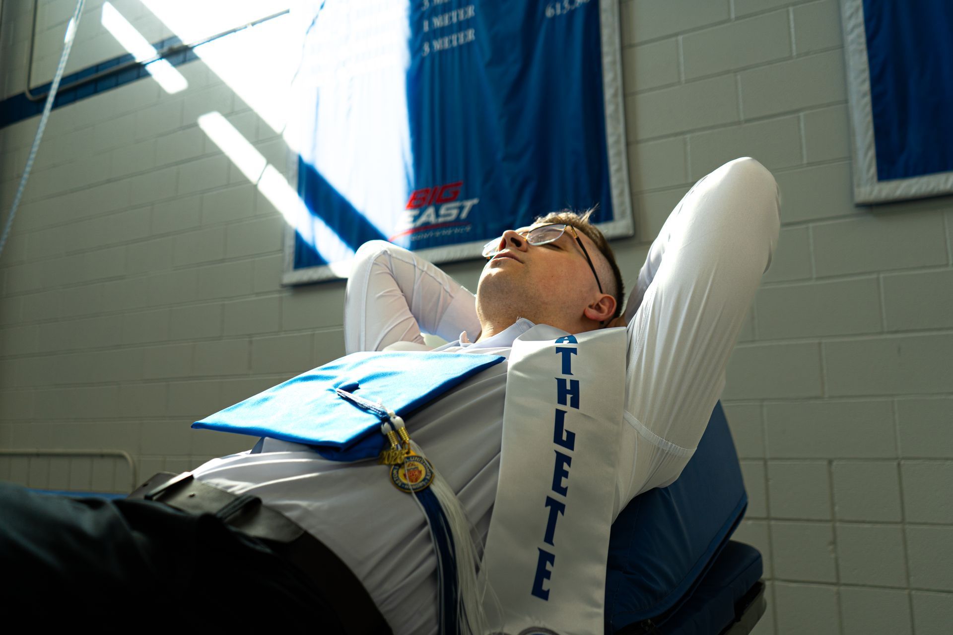 Person reclining on a treatment table, wearing glasses and a blue vest, in a bright clinic room