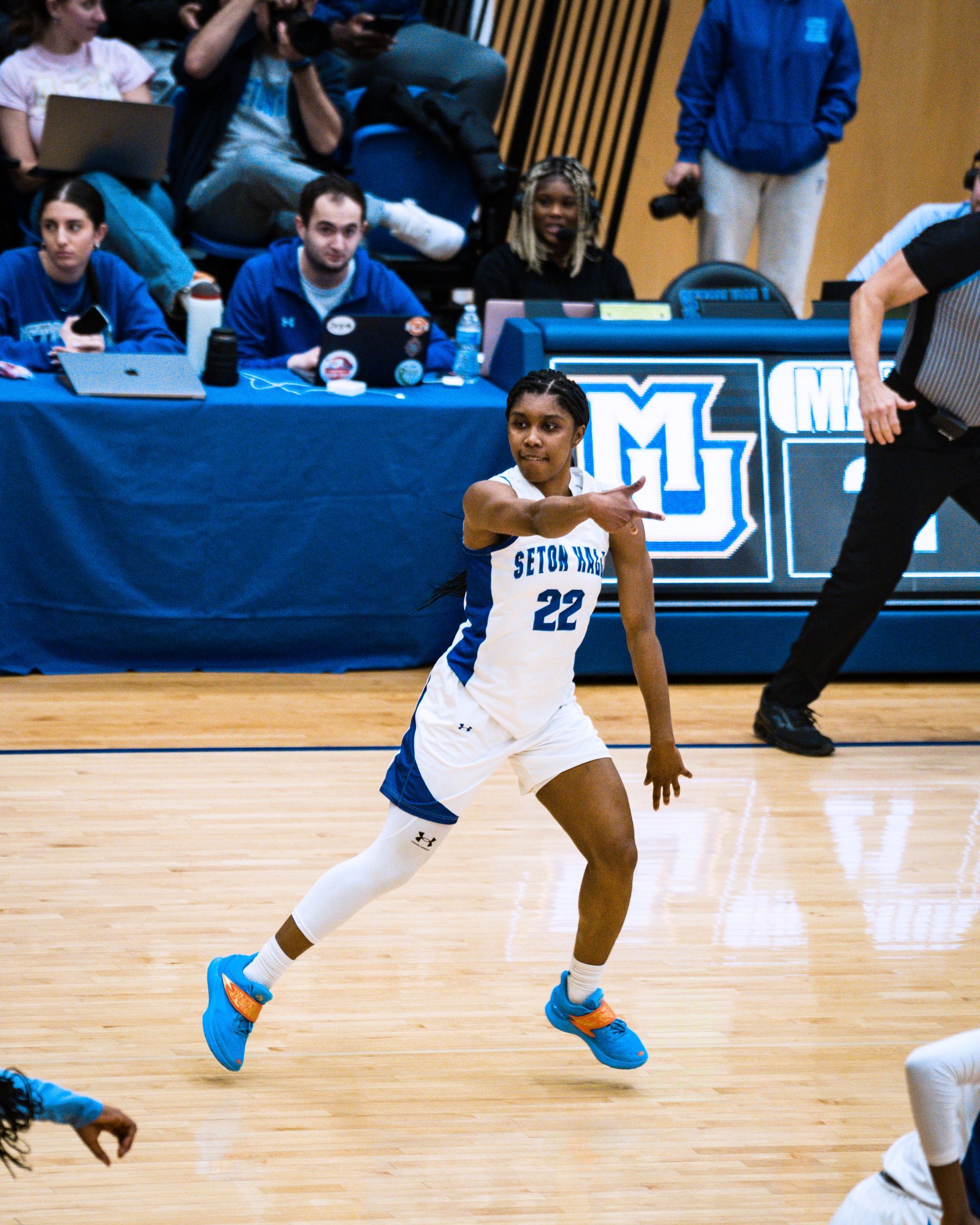 Basketball player in white and blue jersey dribbles on court during a game
