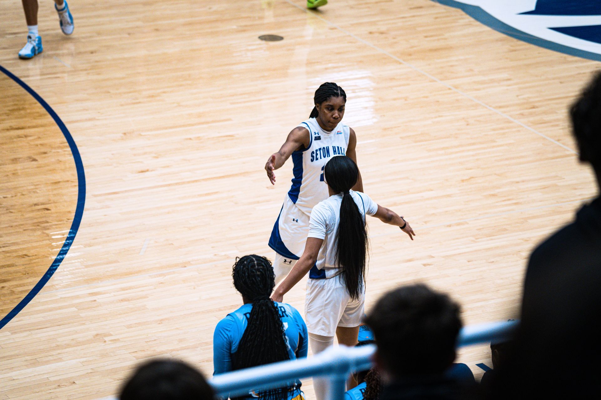 Basketball players in white jerseys on a hardwood court during a game