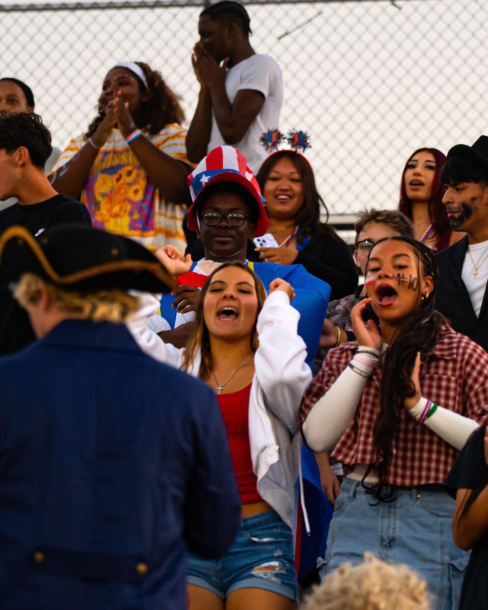 Crowd of cheering fans in bleachers, clapping and shouting at an outdoor event