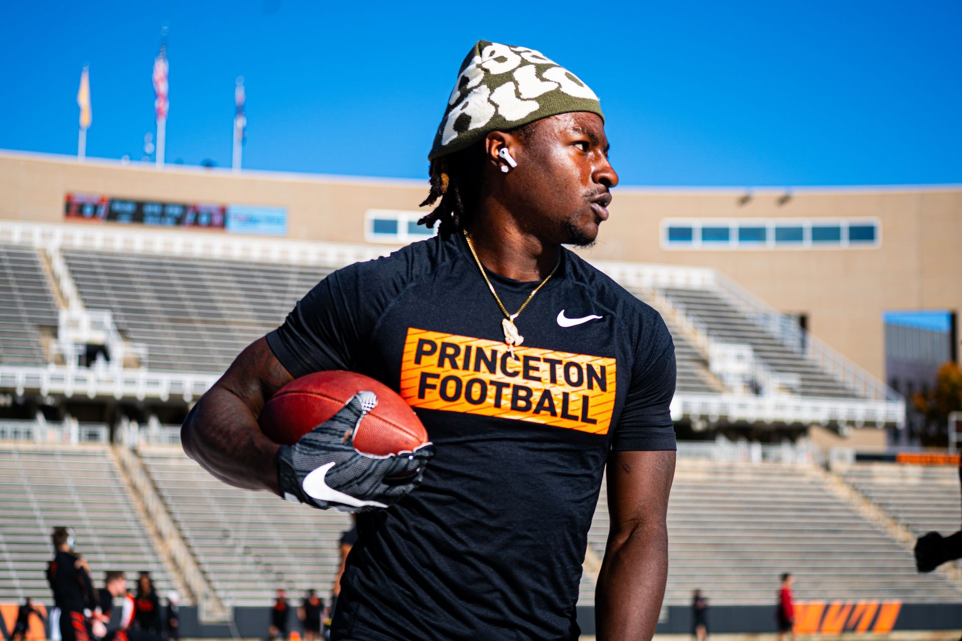 Princeton Football player in black shirt holding a football on a stadium field