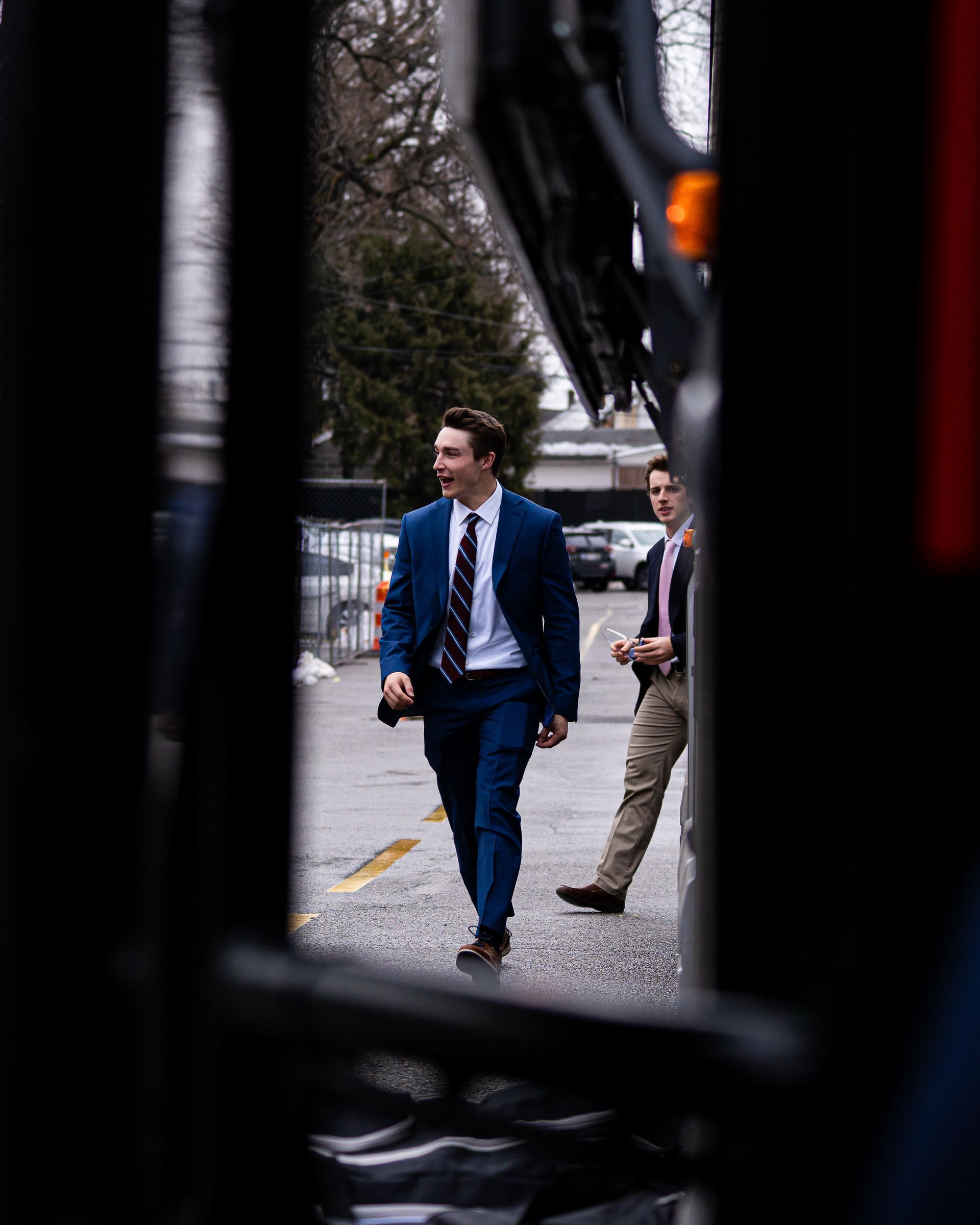 Two people in business attire walking on a city sidewalk, viewed through a dark frame.
