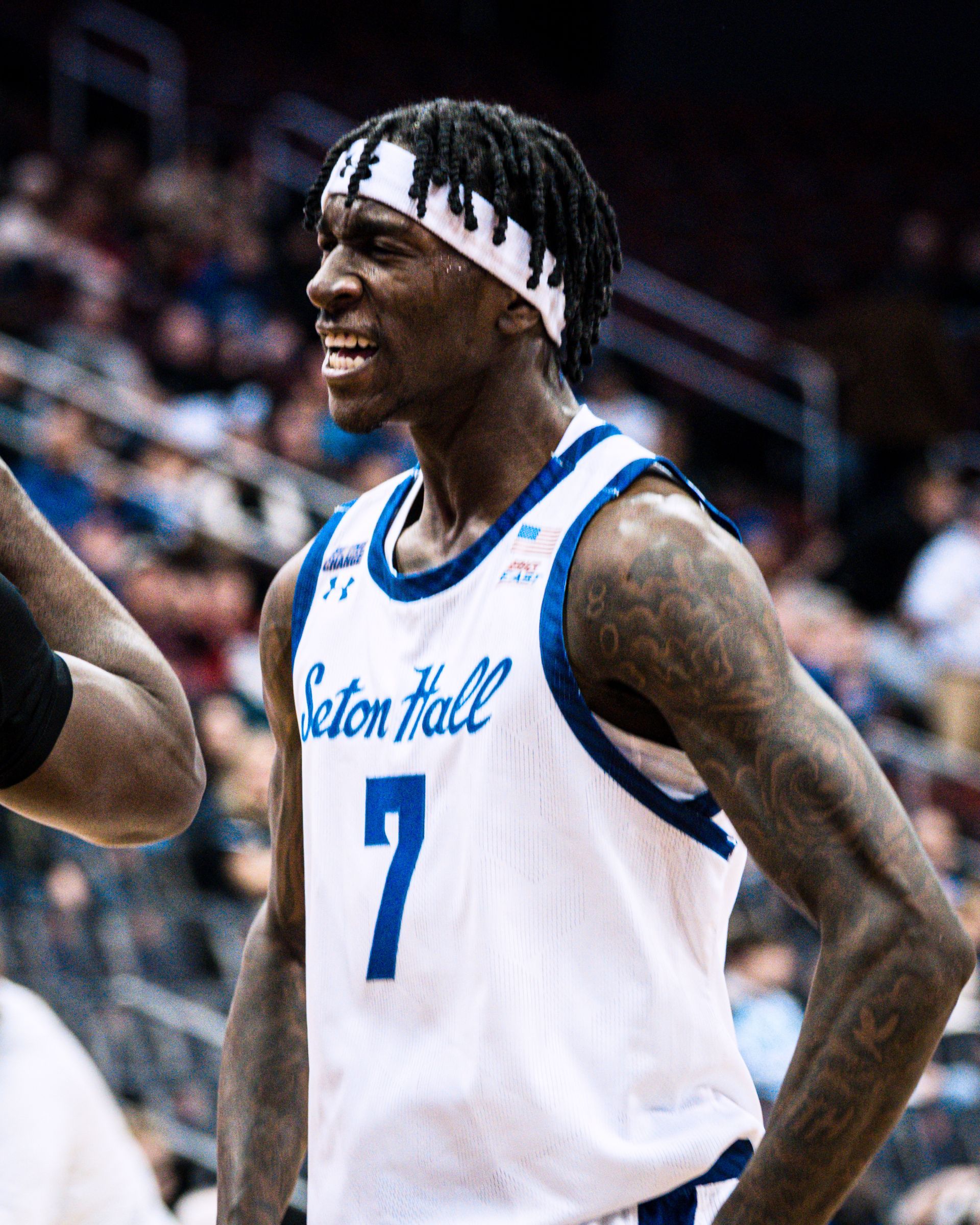 Basketball player in a white Seton Hall jersey #7, smiling on the court