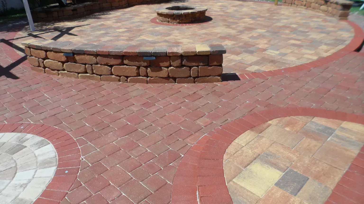 A brick patio with a fire pit in the middle