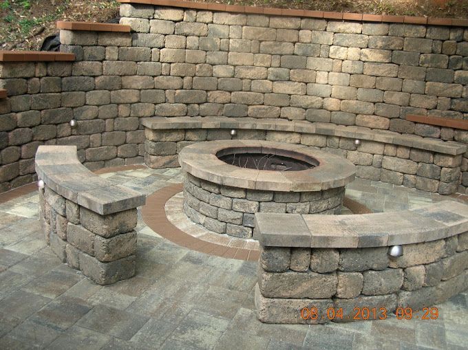 A fire pit is surrounded by a stone wall and benches.