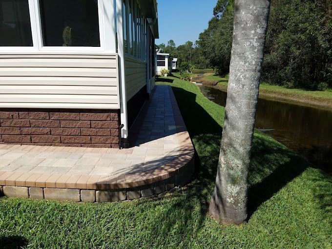 A sidewalk leading to a house next to a body of water