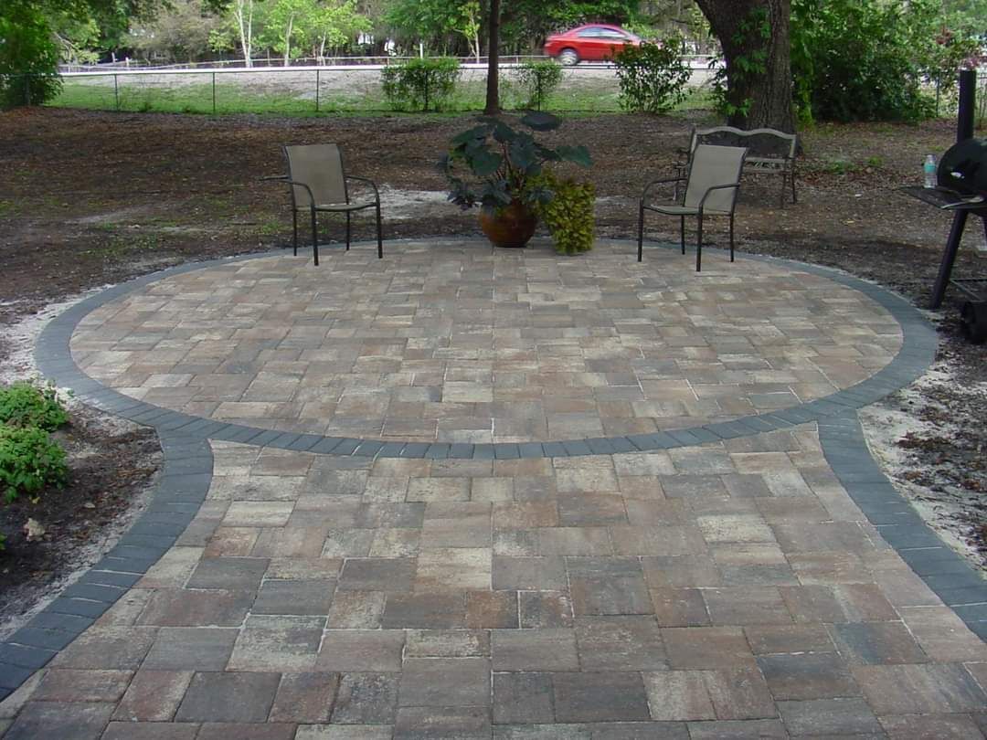 A patio with chairs and a grill in the middle of it.