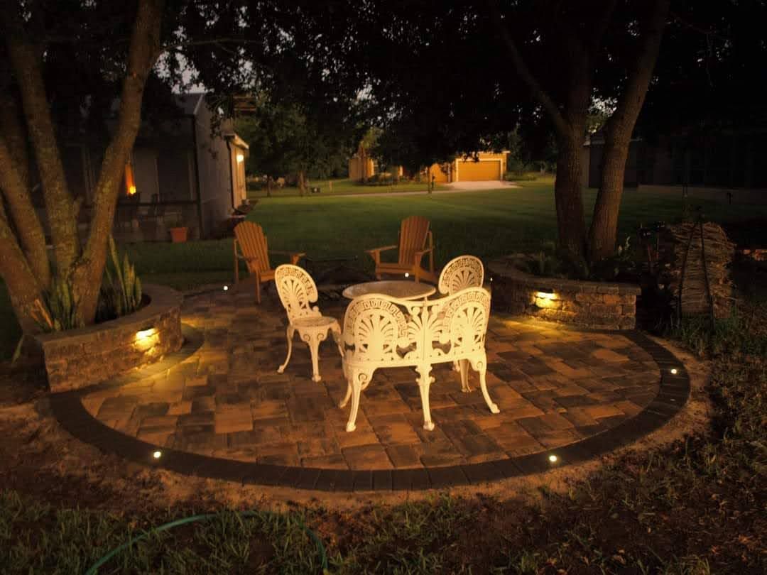 A patio with a table and chairs is lit up at night.