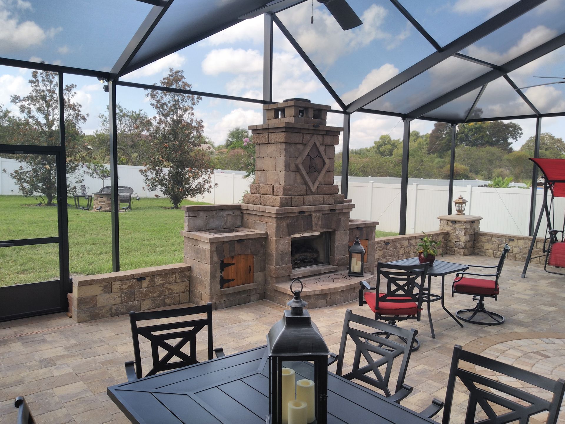 A screened in patio with a table and chairs and a fireplace