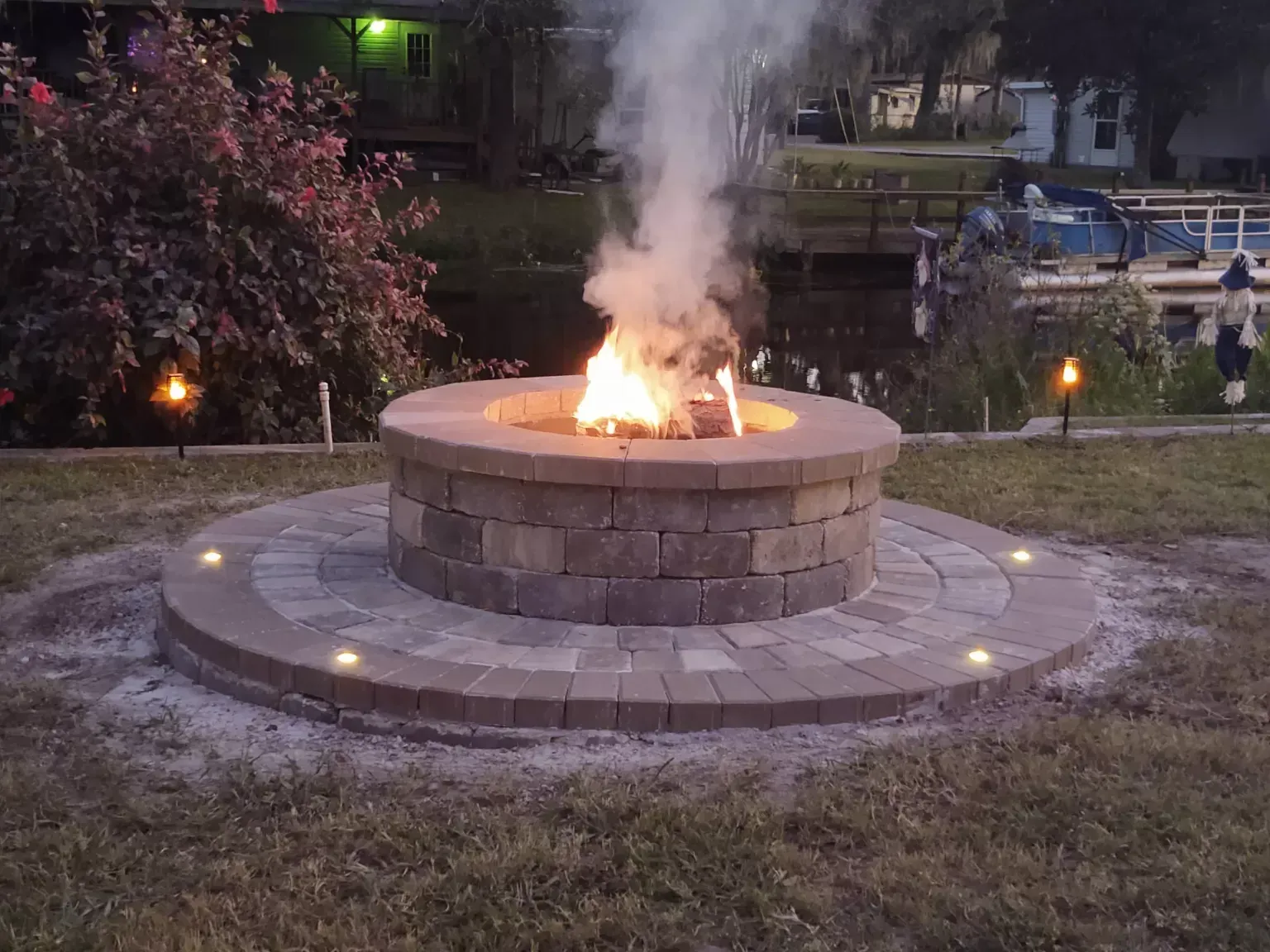 A fire pit is sitting in the middle of a lush green field.