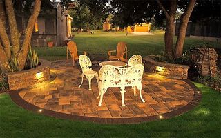 A patio with a table and chairs is lit up at night.