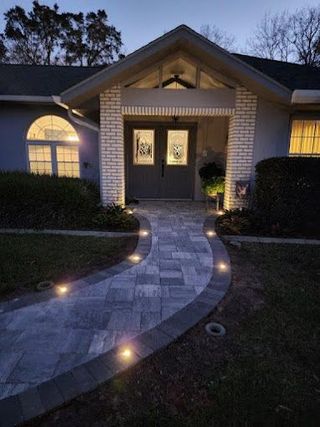 A house with a walkway leading to the front door at night.